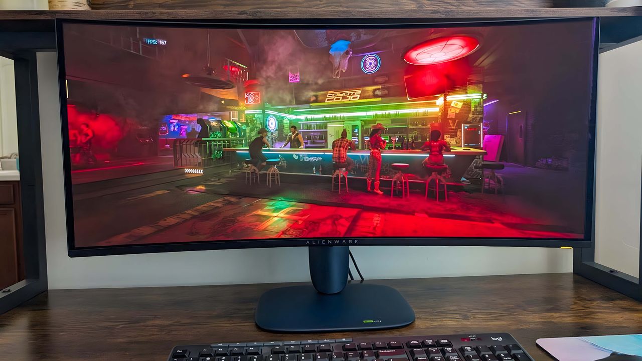 Alienware 34" Curved QD-OLED AW3425DW Gaming Monitor displaying a bar scene from Cyberpunk 2077 with several colorful neon lights in it.