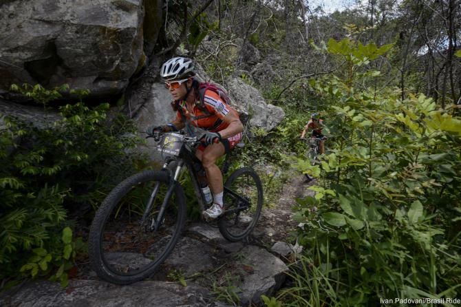 A woman climbs some technical singletrack