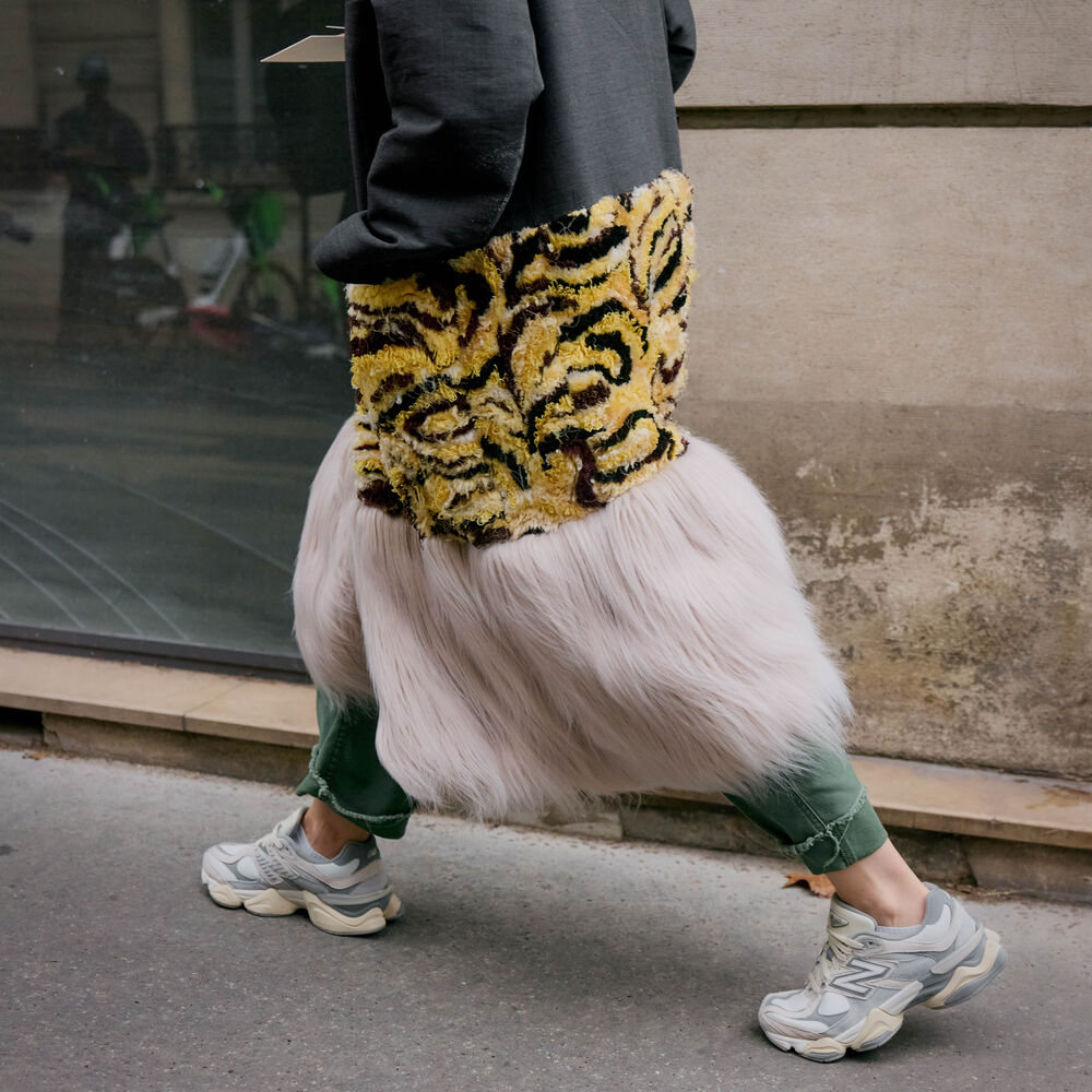 Model wears sneakers and textured dress. 