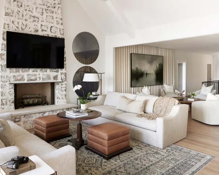 a neutral living room with brown leather stools