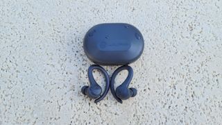 The JLab Go Air Sport wireless earbuds and charging case being dislplayed on the concrete