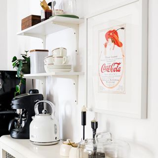 White coffee bar with retro framed wall art and tiered open shelving