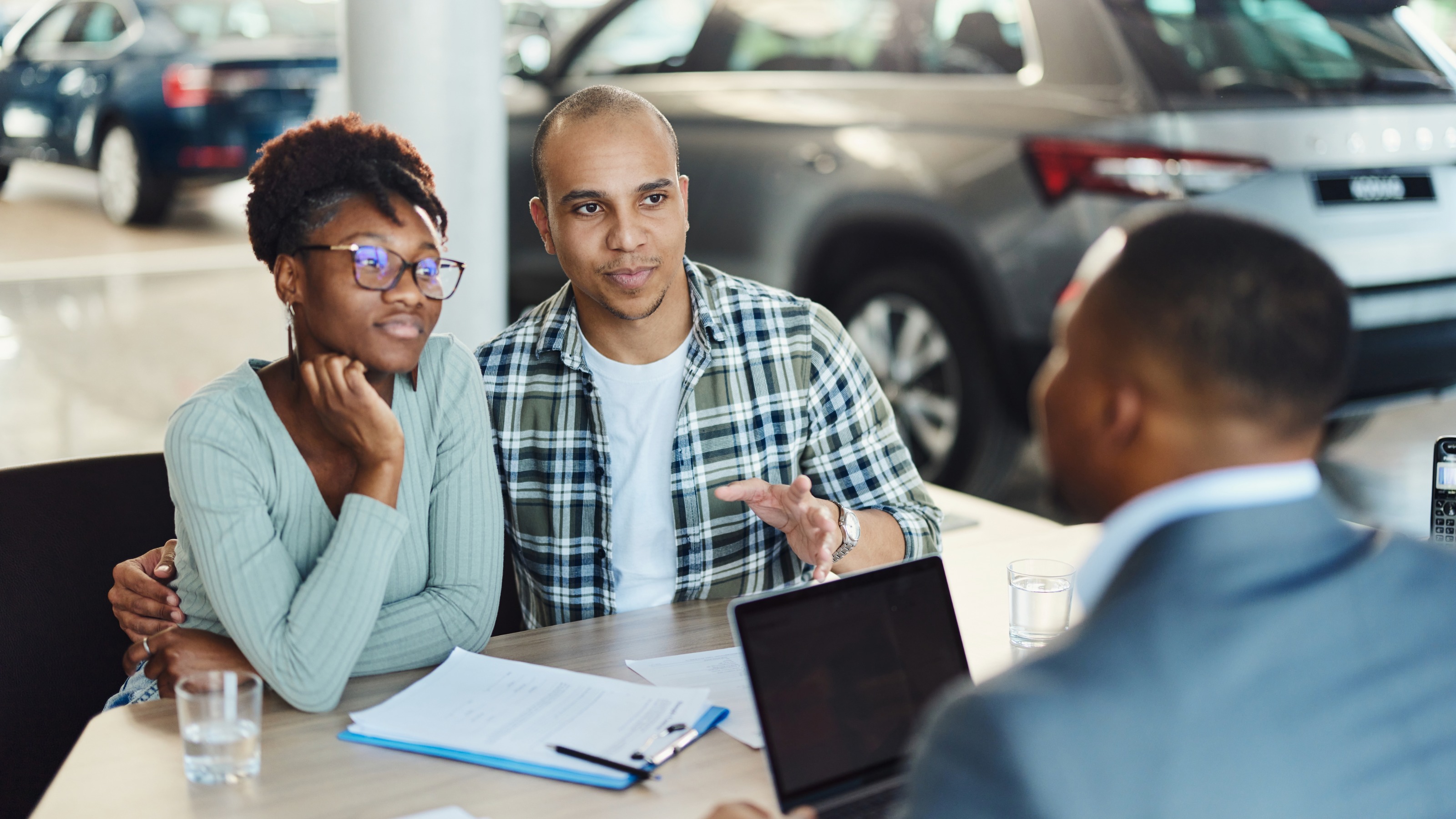 Couple communicating with a car salesman in showroom