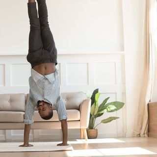 Happy young adult doing handstands in a living room