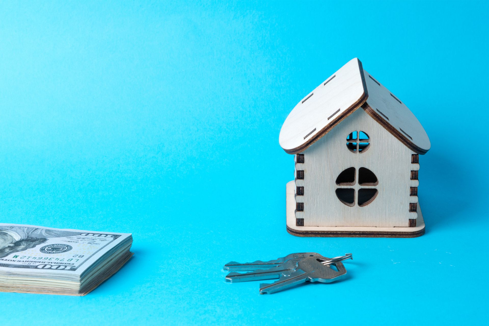 rendering of a white toy house with money and house keys nearby
