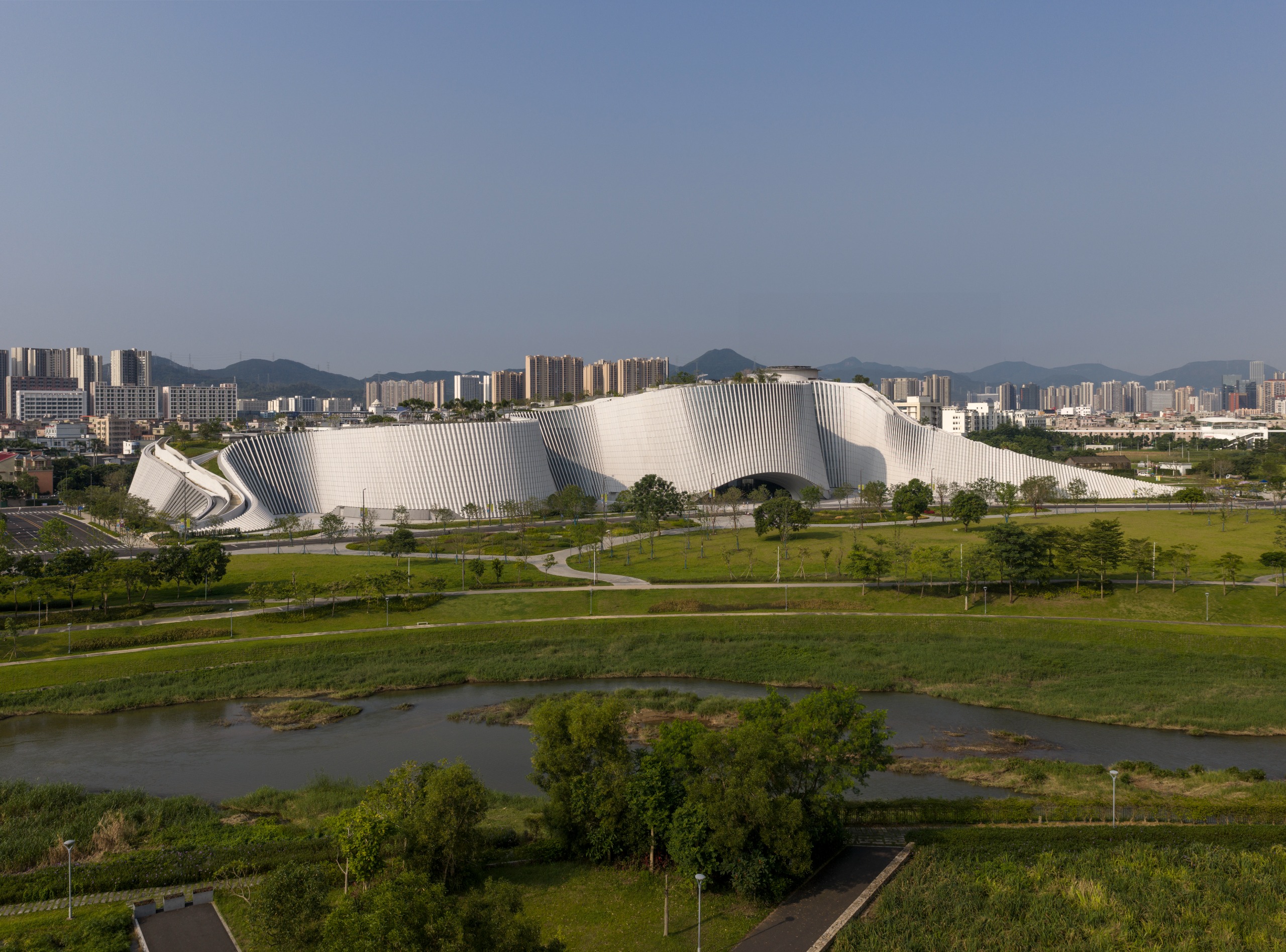 undulating forms of the Shenzhen Natural History Museum by 3XN, B+H Architects and Zhubo Design in a green park