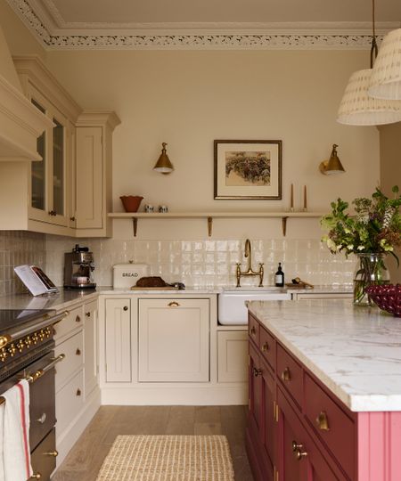 A white kitchen with a red island and glossy backsplash tiles