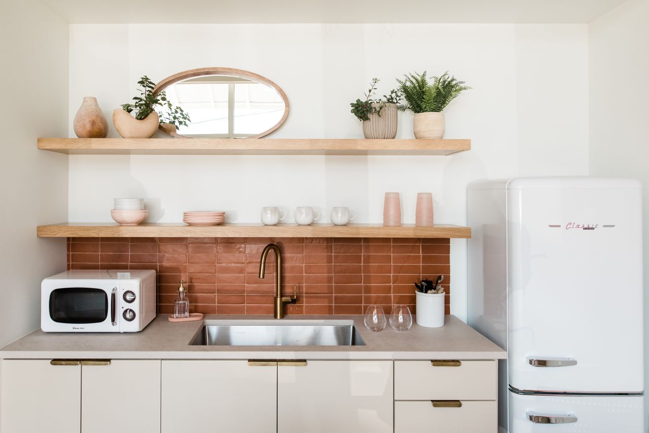 A kitchen sink with a red tiled backsplash