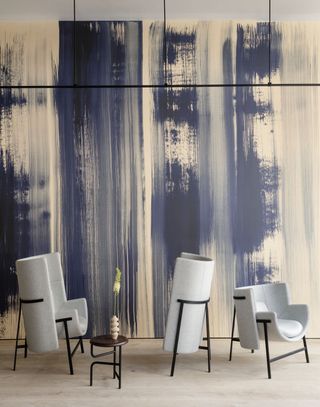 Wallpaper with hand-painted blue stripes with furniture display including three grey armchairs and a small table