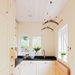 Utility room kitchen area with cream cupboards and a hanging clothes rack on the ceiling