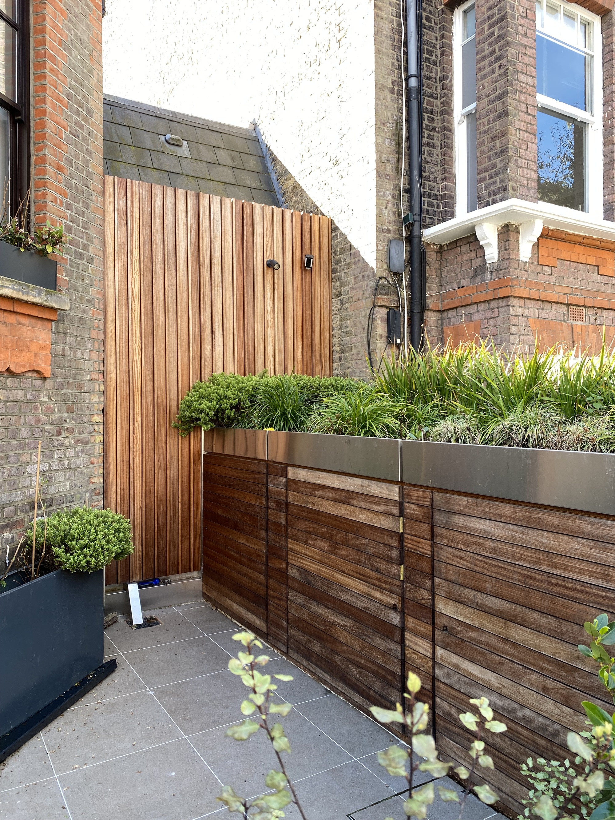 outdoor storage for bikes in wooden outdoor planters in front of a london townhouse