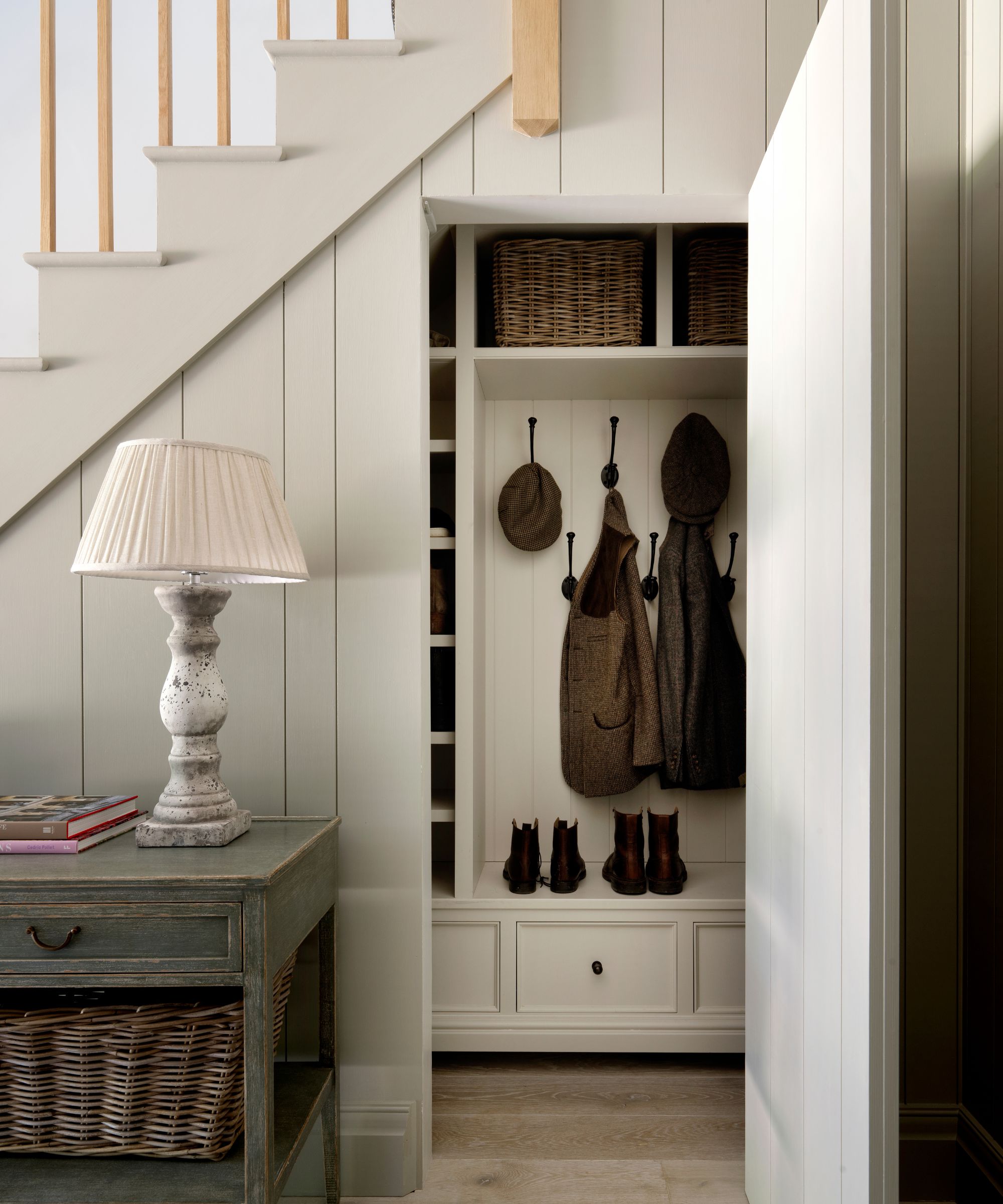white panelled painted staircase with a boot room hidden underneath behind a concealed door that opens up to boot and coat storage