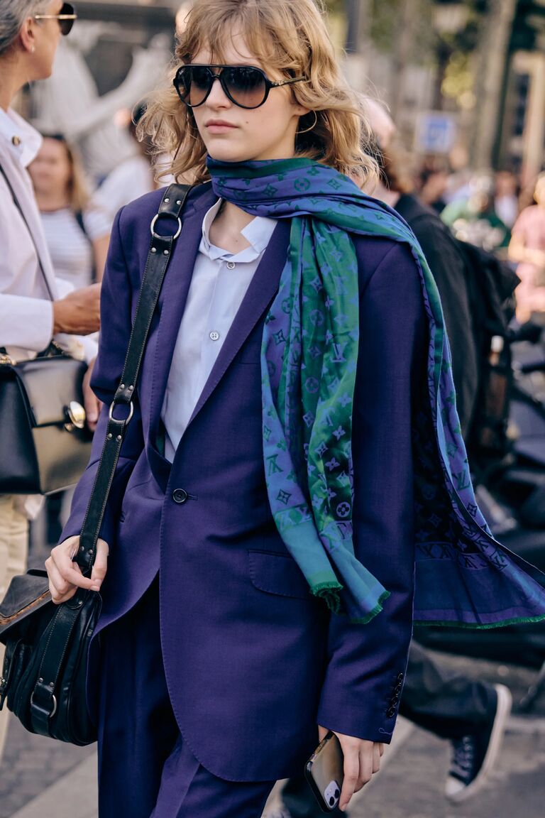 a woman wearing a purple suit, purple shirt, and blue purple scarf