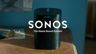 Paras älykaiutin Sonos One puisella pöydällä sinistä seinää vasten