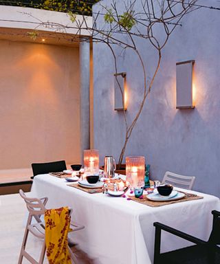 An outdoor dining scene will wall lights above