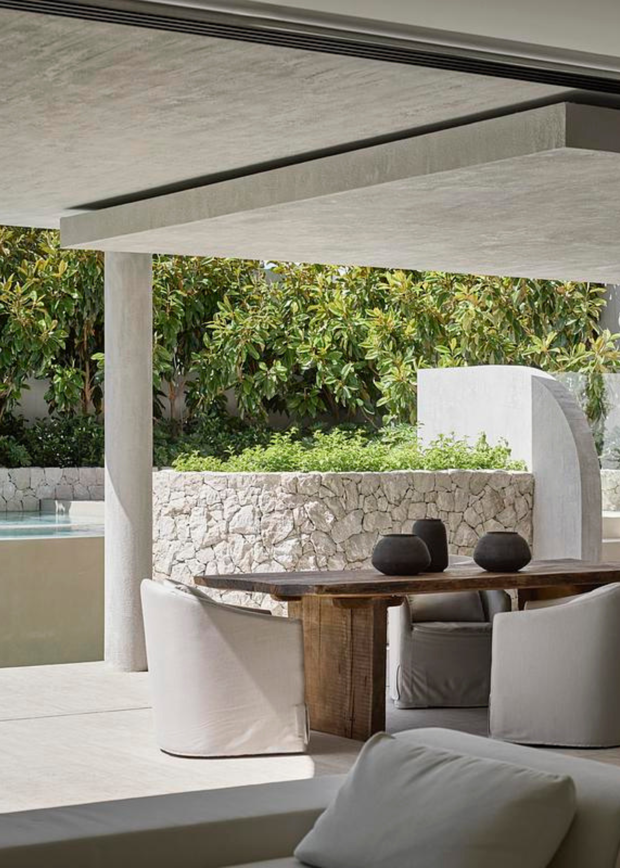 An outdoor dining space under open roofing, near a pool