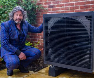 Laurence Llewelyn-Bowen bent down next to a heat pump