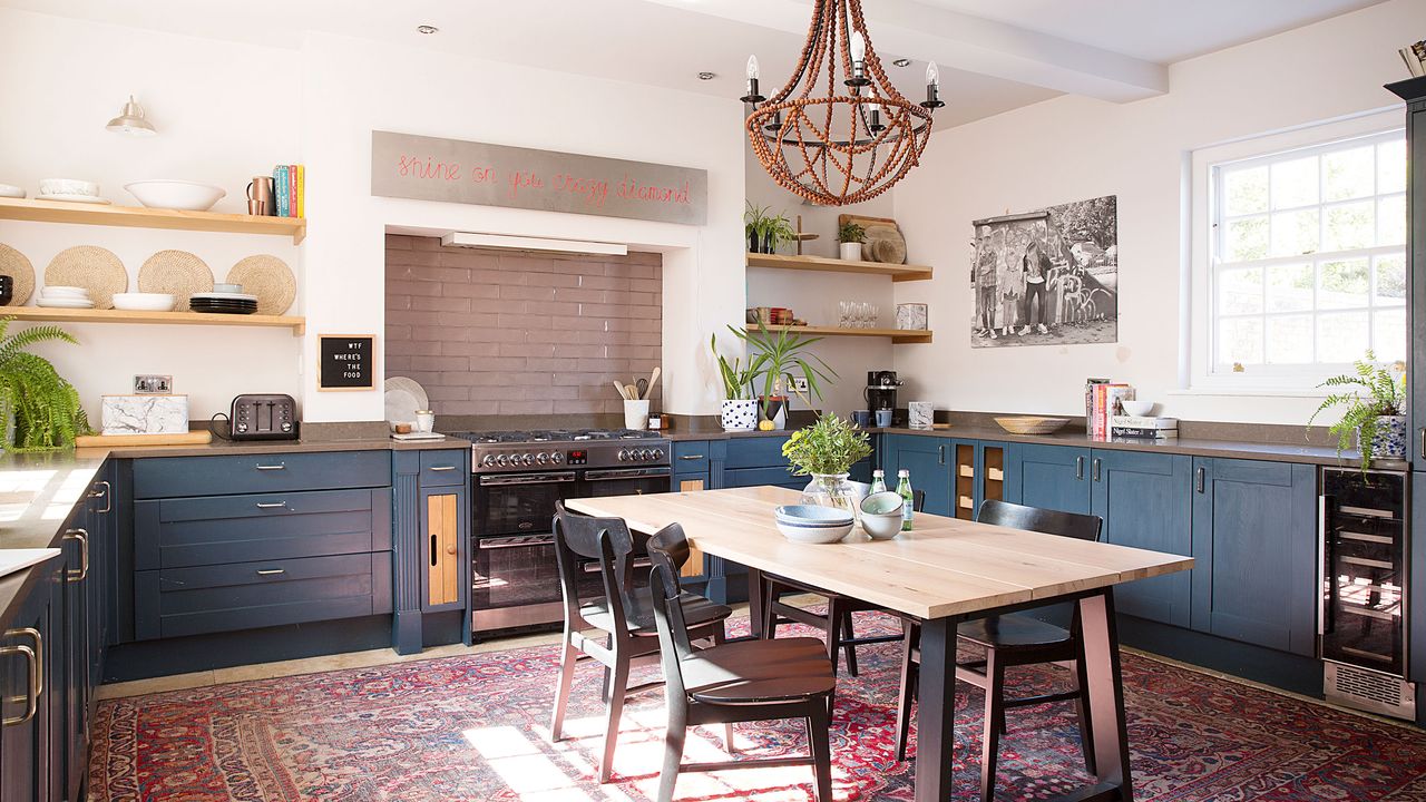 Kitchen-diner with dark blue kitchen units and large table in the centre of the room