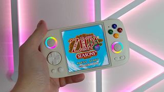 Anbernic RG Cube with Zelda: Oracle of Seasons title screen on display and pink lights in backdrop