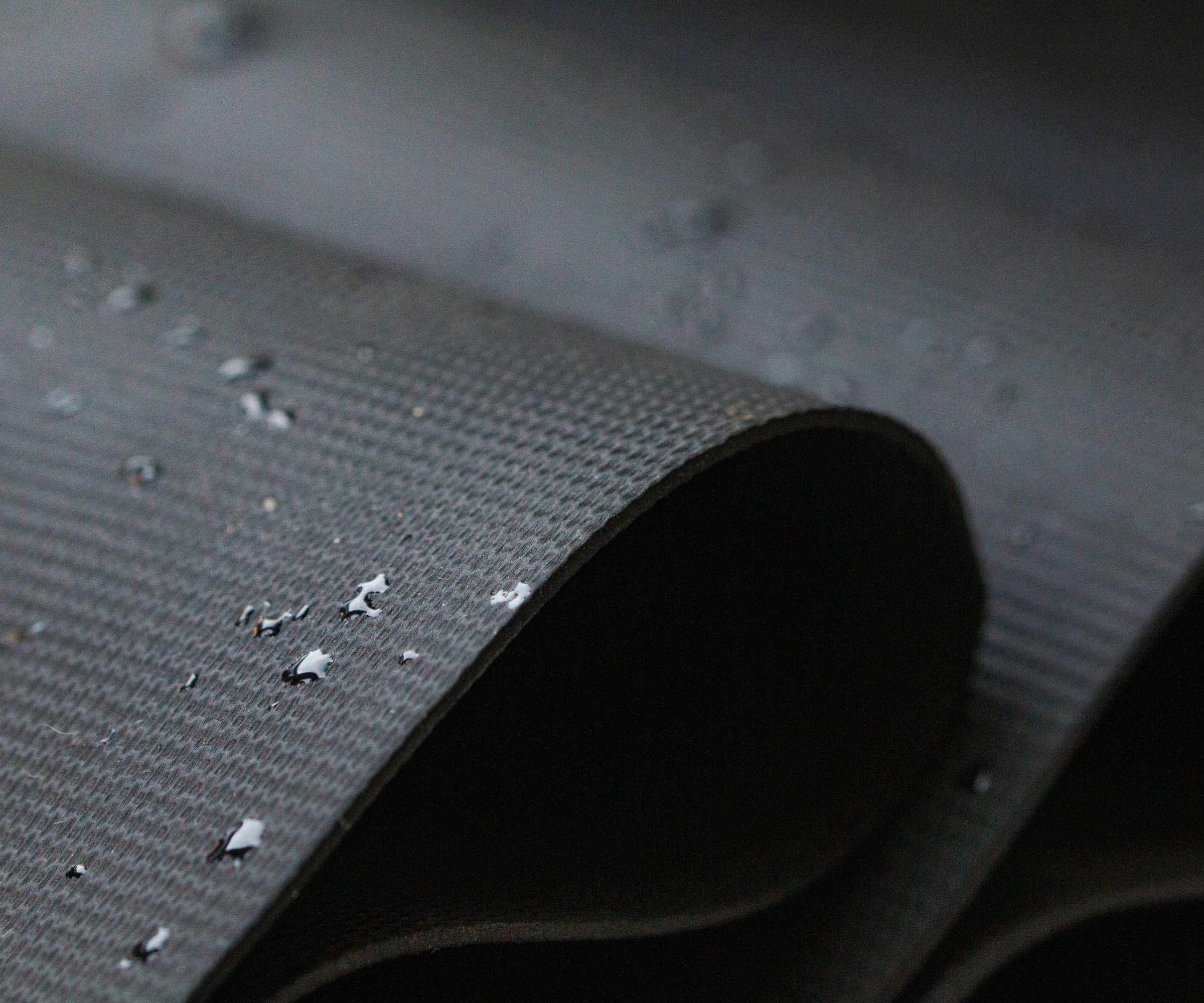 Rubber EPDM roofing close-up, rolled, with drips on water on surface