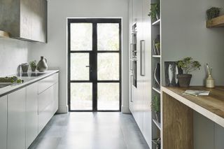 Modern white galley kitchen with glossy cabinets and a black Crittall door