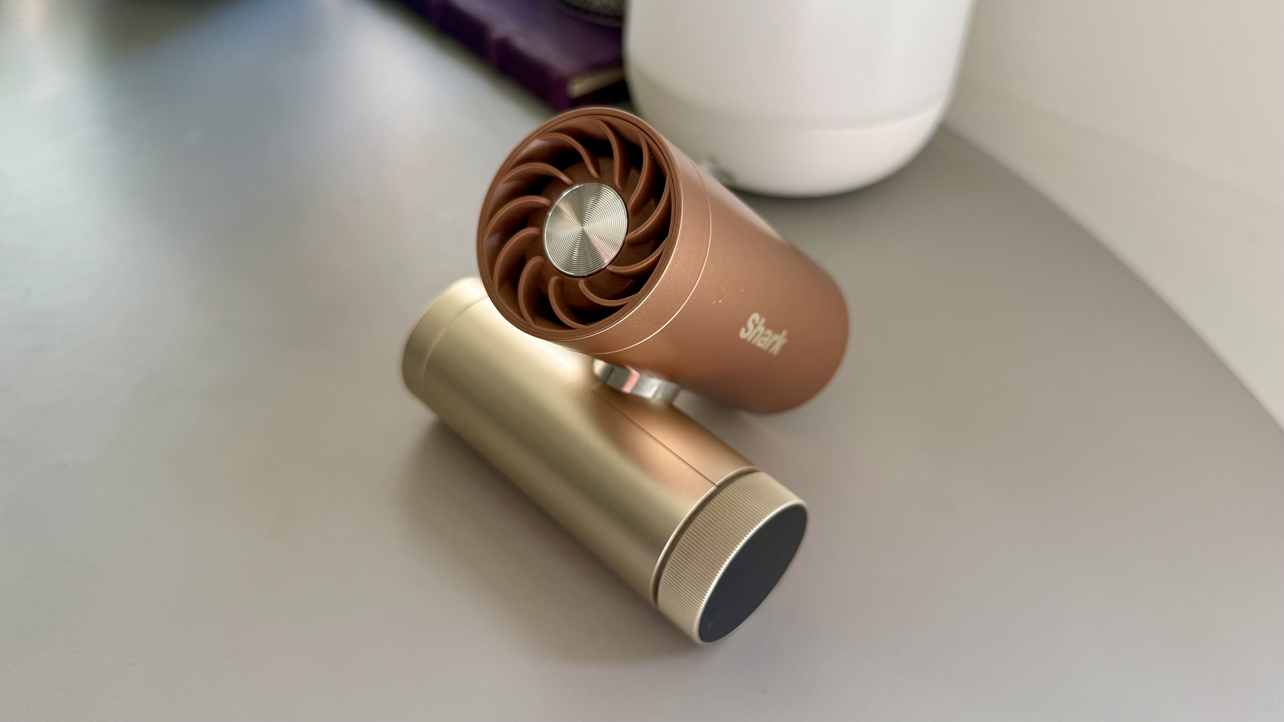 The shark chillpill portable fan in the shade latte pictured on a grey table