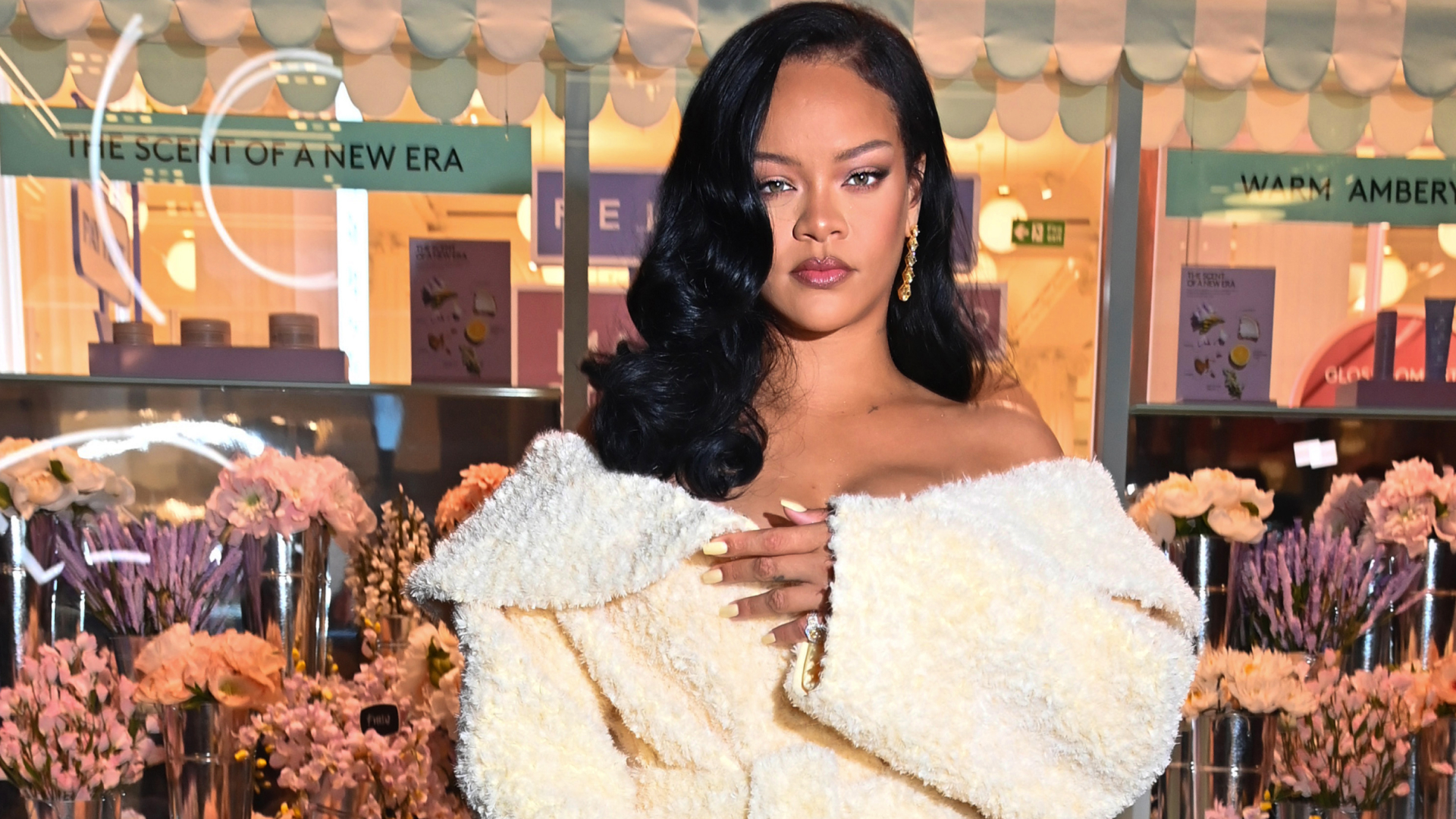 Rihanna wearing a curled side part hairstyle and a textured jacket as a dress.