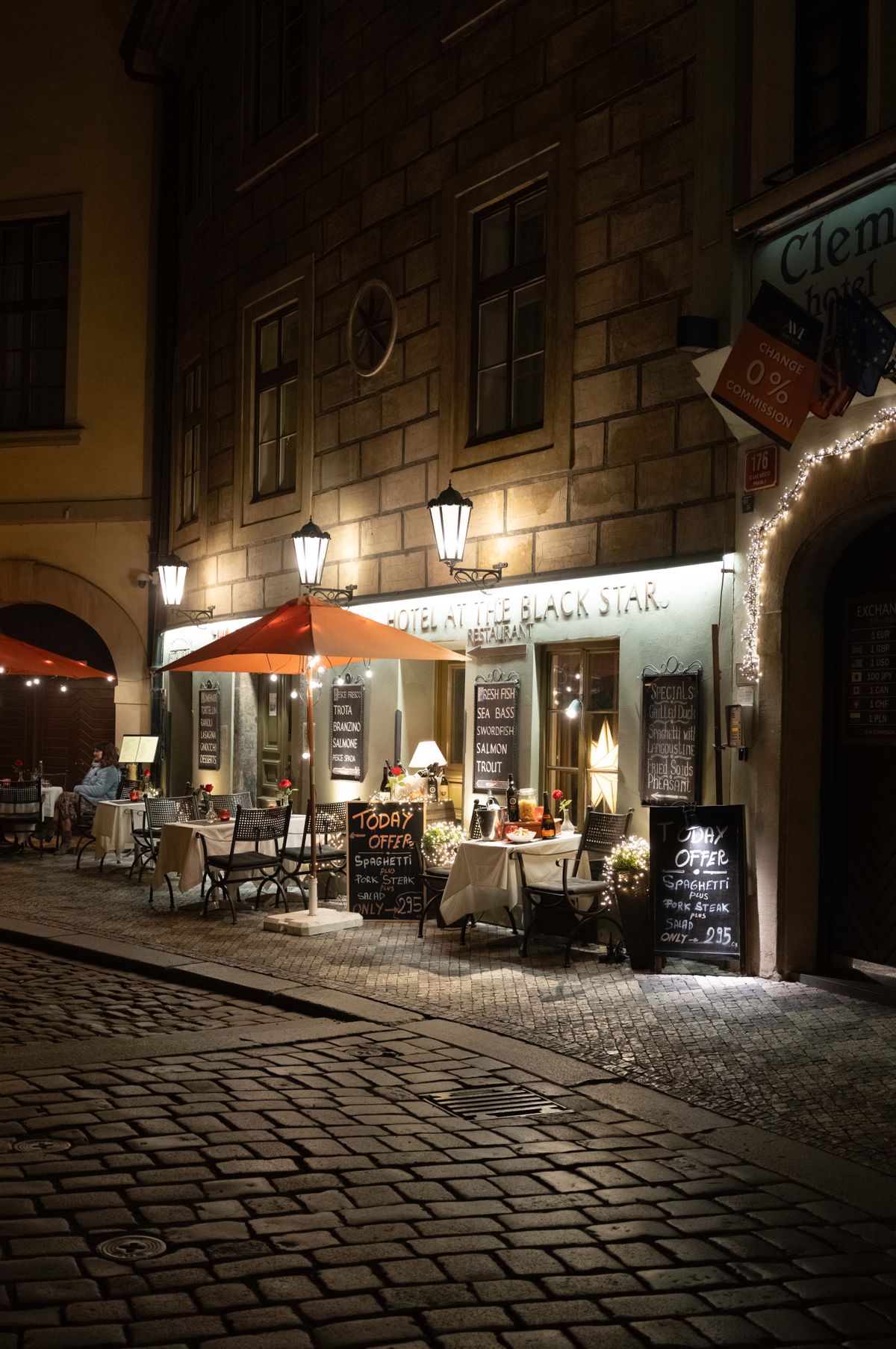 A restaurant in Prague on a cobbled street lit up at night