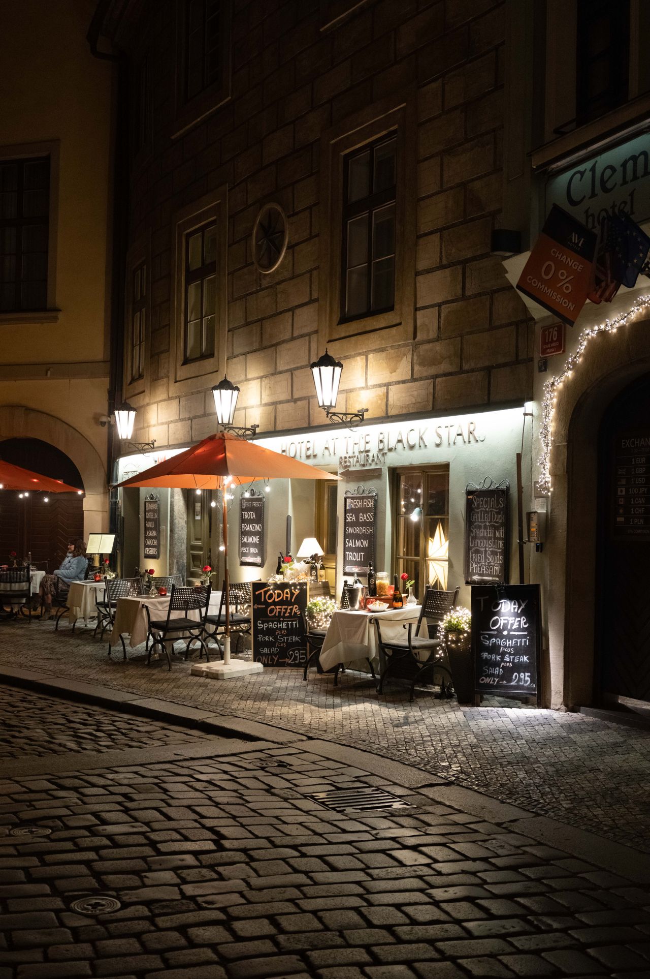 A restaurant in Prague on a cobbled street lit up at night