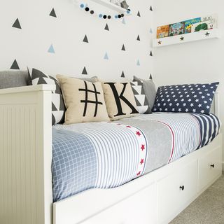 childrens room with wallpaper on wall and sofa with cushions