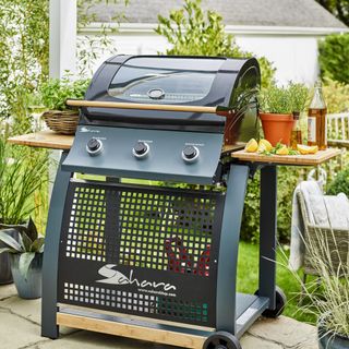 Large black BBQ on wheels with grill gate on patio