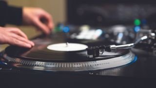 A man DJ-ing on vinyl decks
