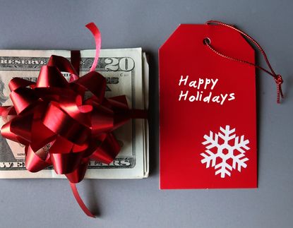 Stack of $20 bills with a red gift bow on top and a red gift tag that says "Happy Holidays."