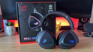 Asus ROG Delta II gaming headset leaning against packaging on a wooden desk