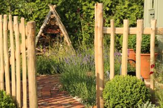 rustic garden ideas: natural wood fence, brick path and bug hotel