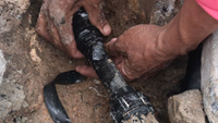 a person fixing a leaking underground water pipe