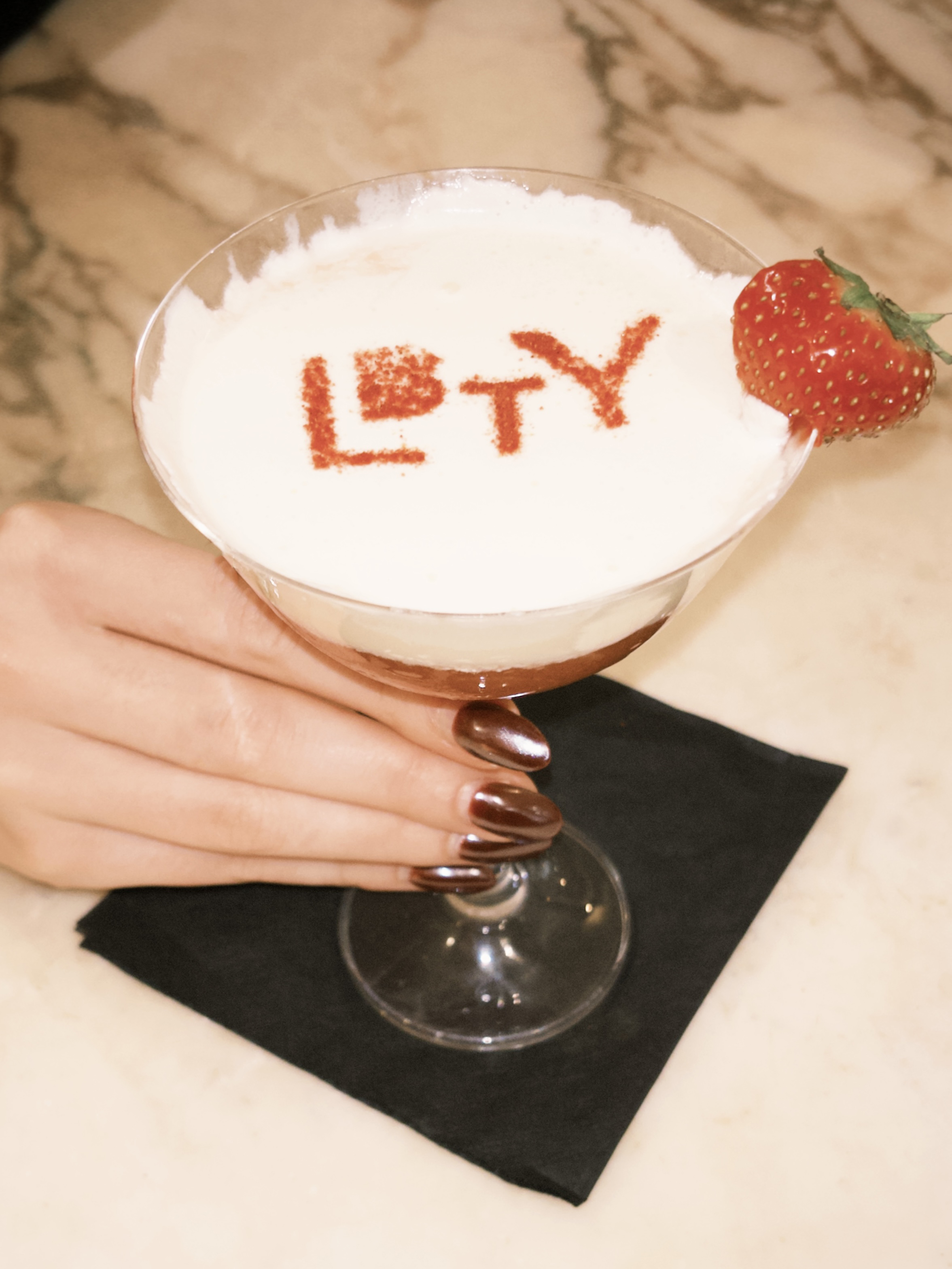 Cocktail in a martini like glass with a strawberry garnish