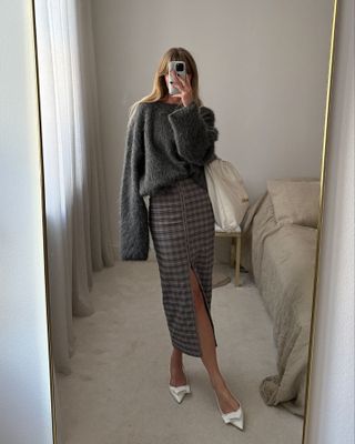 Jeanette Madsen in a gray sweater and plaid pencil skirt.