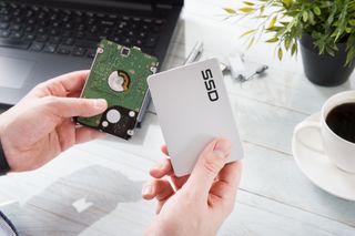 A person holding an SSD and HDD.