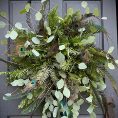 A potato wreath on black front door. It is grafted from eucalyptus, fir and peacock feathers.