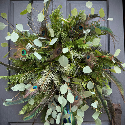 A potato wreath on black front door. It is grafted from eucalyptus, fir and peacock feathers.