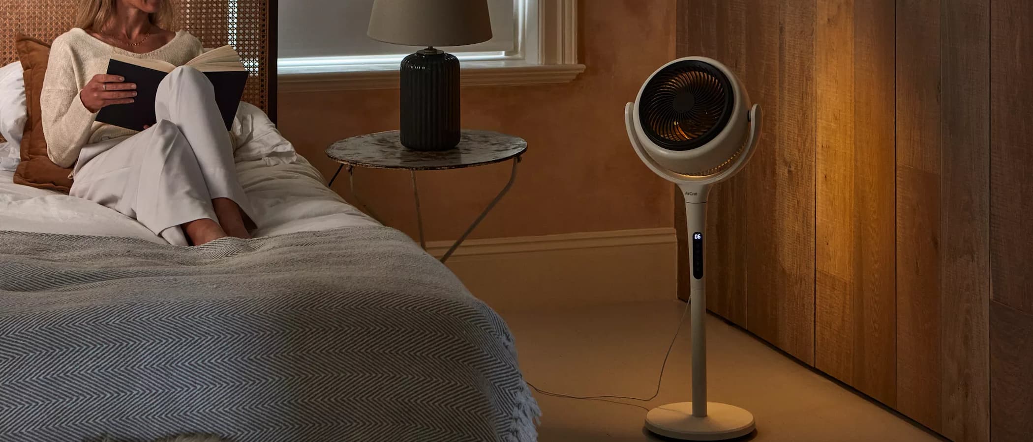 A Lume Air Circulator fan next to a bed