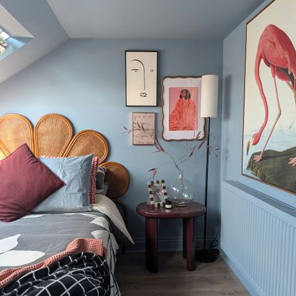 Blue eaves bedroom with rattan scalloped headboard, art of walls, bedside table and floor lamp