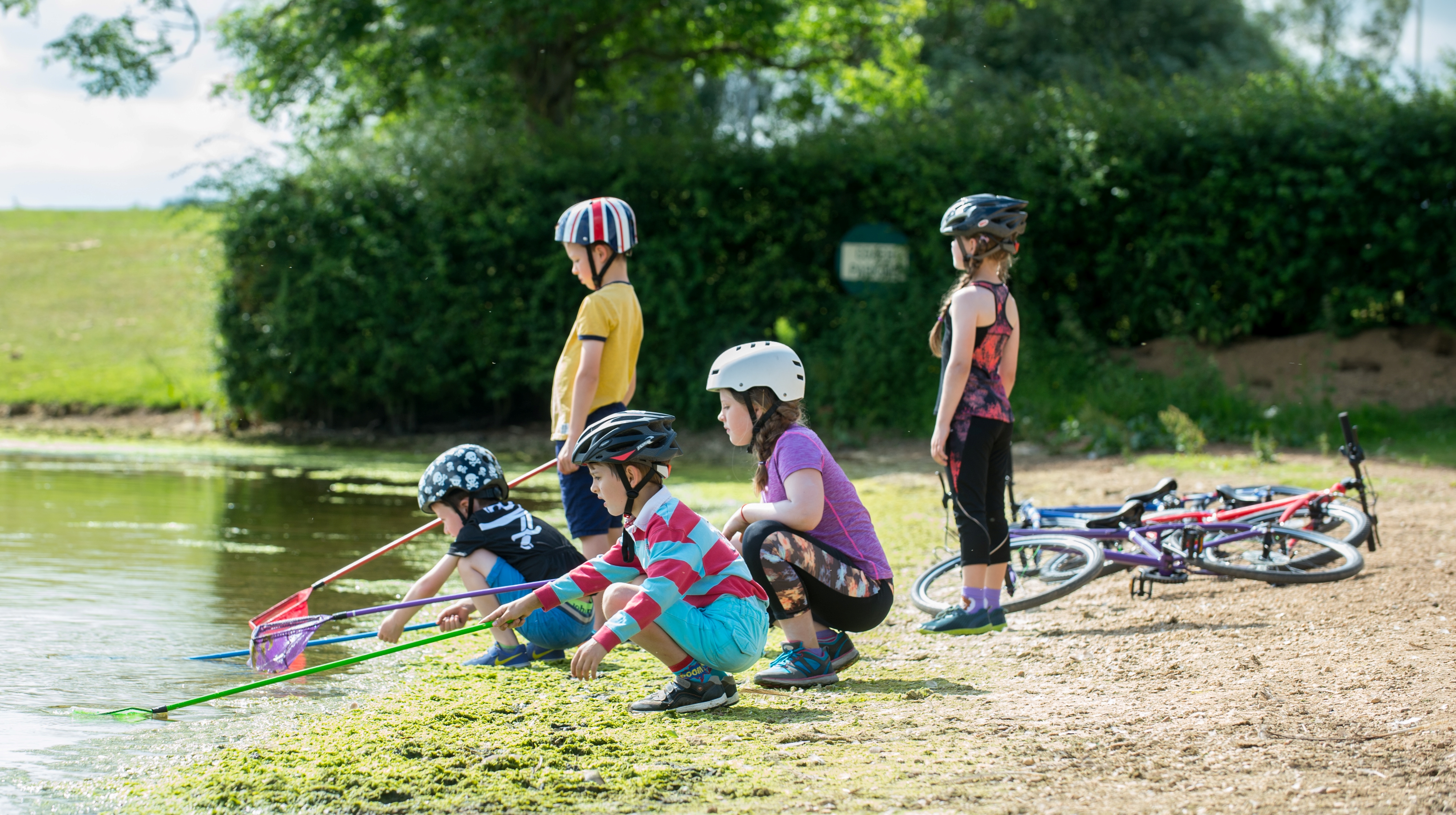 Kids bike helmets by a pond