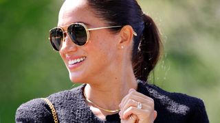 Meghan Markle wearing black sunglasses with gold details and gold jewellery