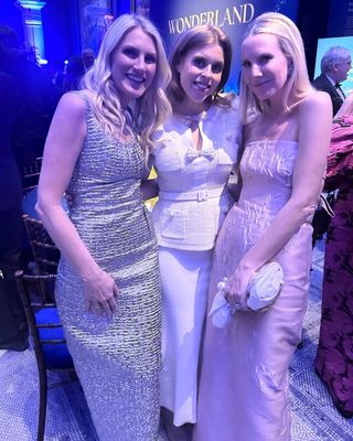 Princess Beatrice wearing an ivory dress with bows posing with two friends in long dresses