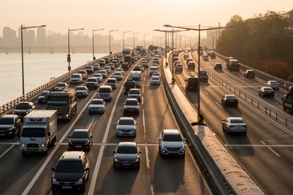 Vehicles on the interstate with city skyline in distant background. 