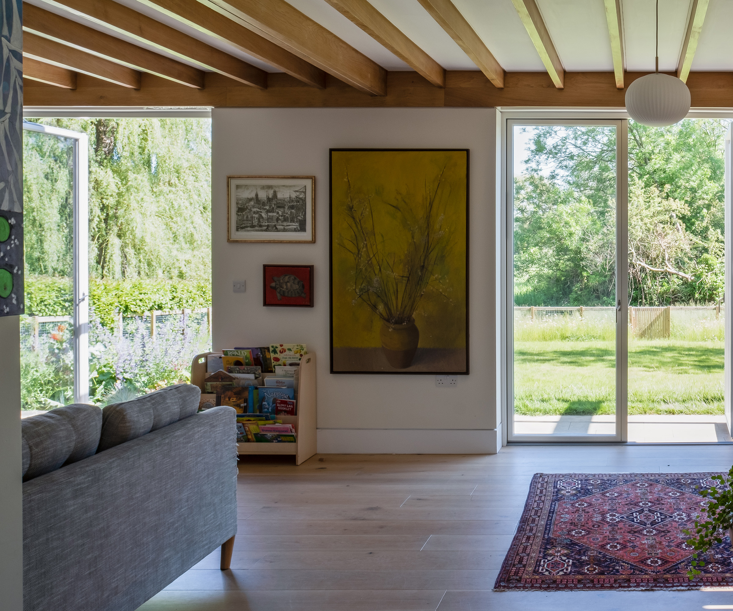 A living room with large glass doors looking out to a pleasant garden on a sunny day