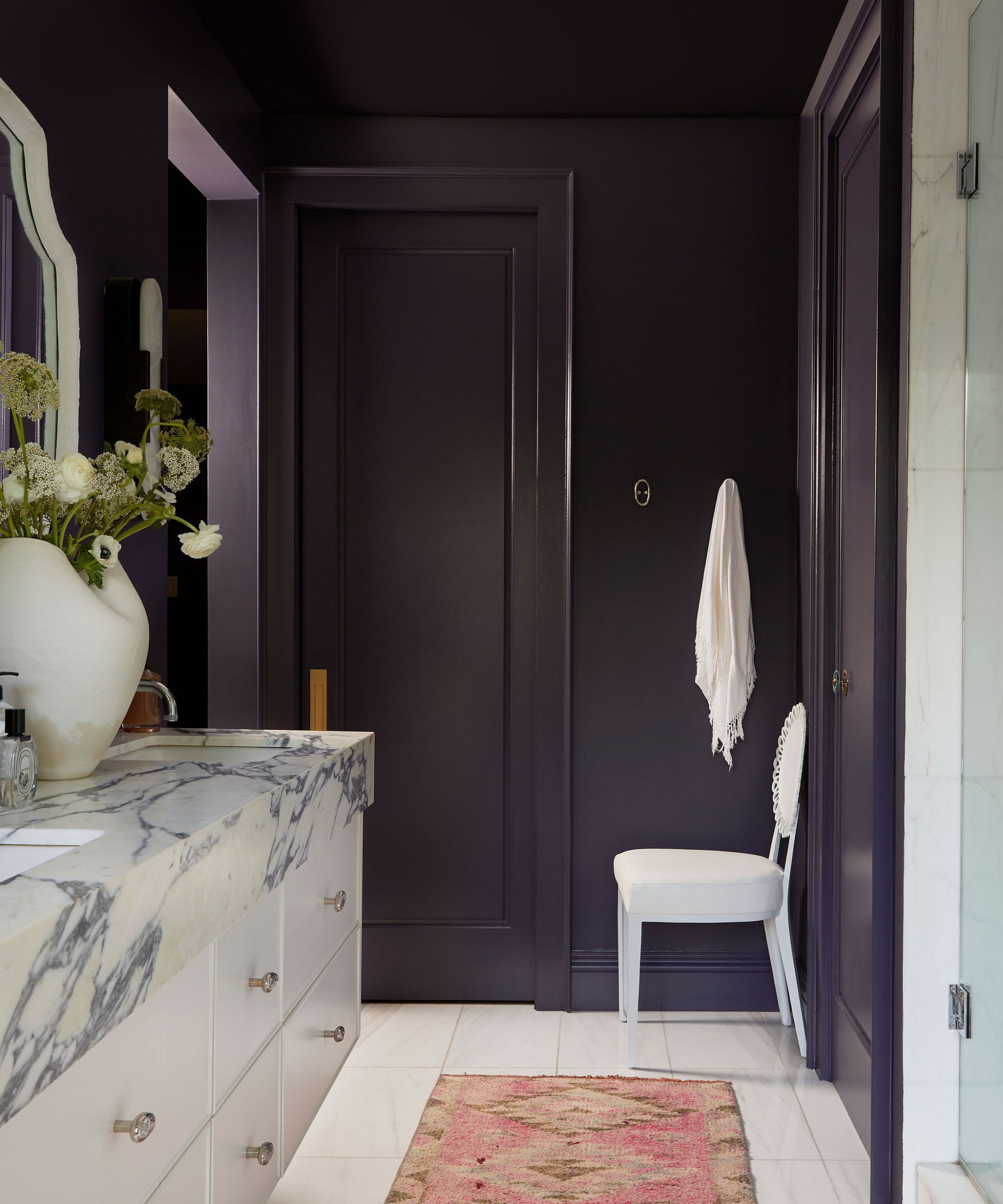 A deep purple bathroom with a white vanity and marble top