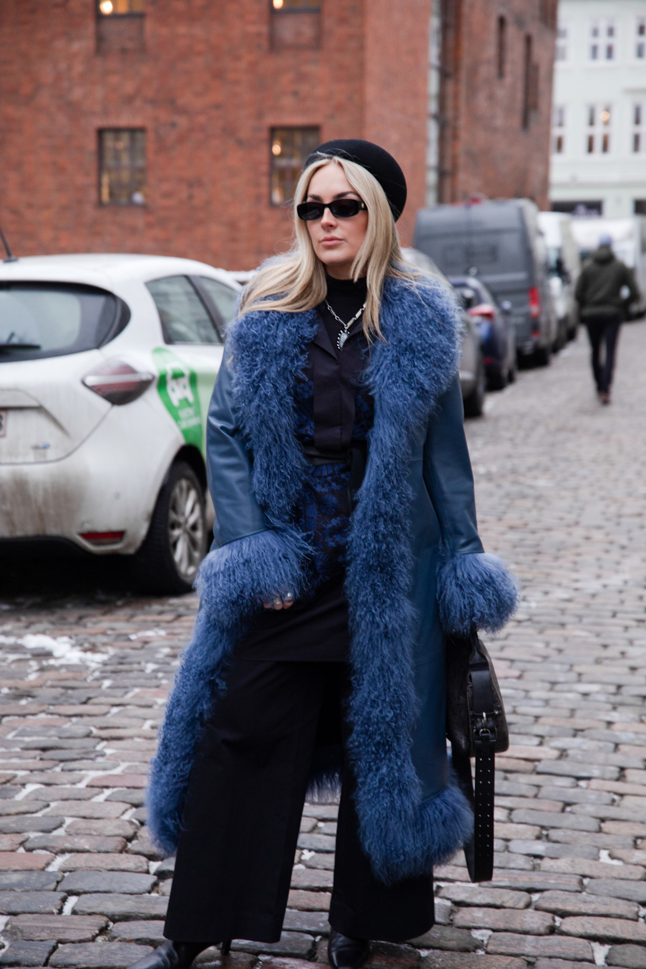a copenhagen fashion week guest wearing a fur trimmed coat and black hat